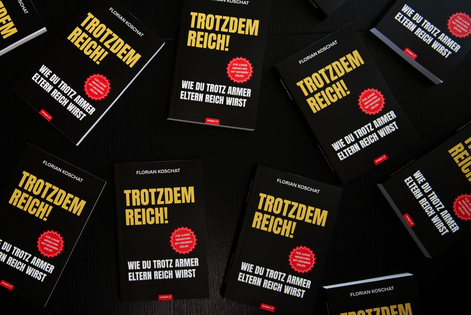 Viele Exemplare von „Trotzdem reich!“ auf einem dunklen Tisch